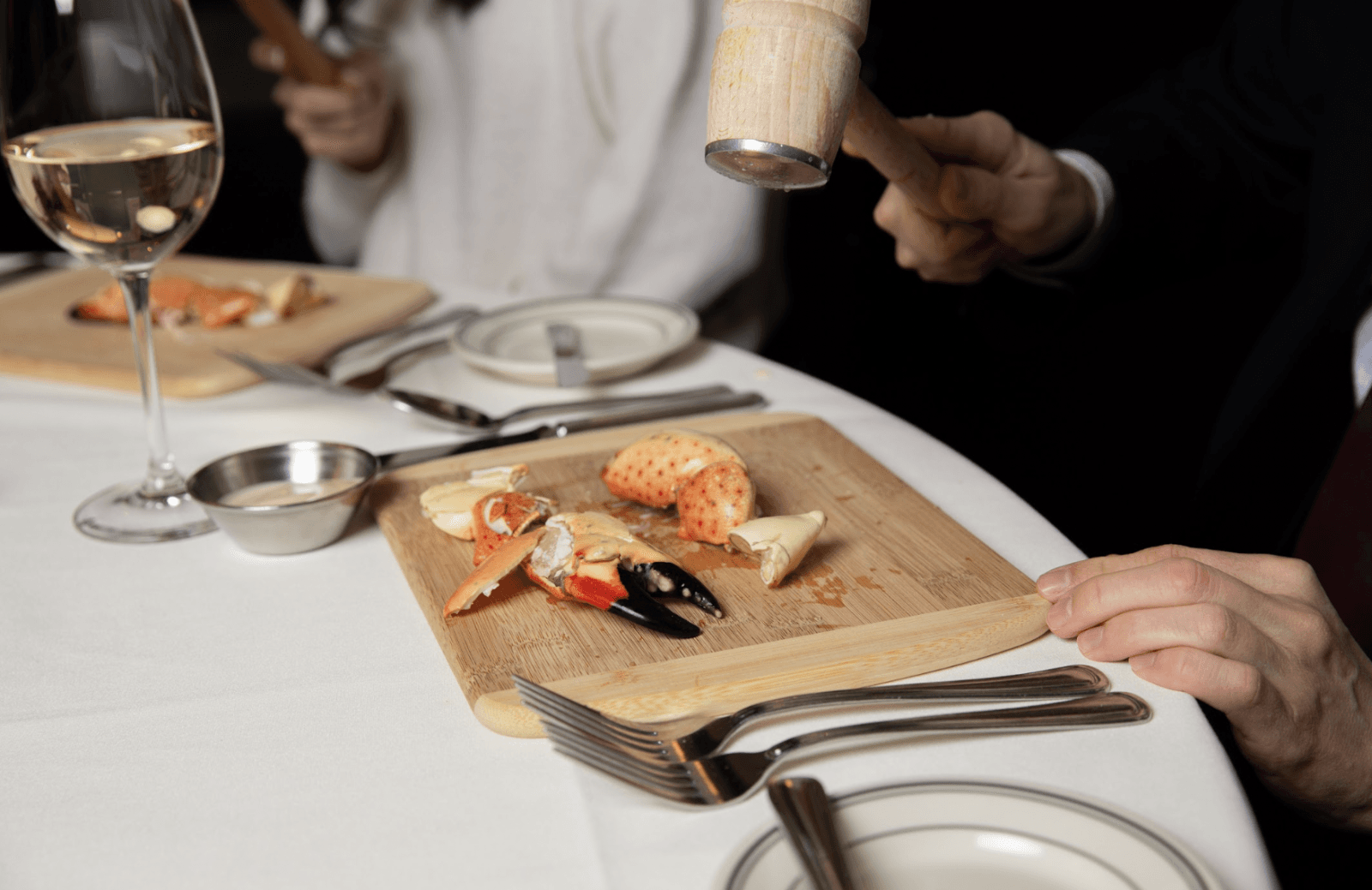 cracking stone crab on a wooden cutting board with white wine in the back