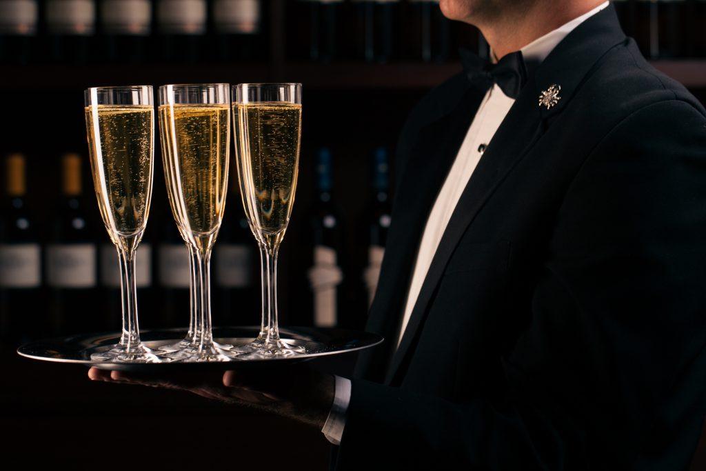 a waiter holding three glasses of champagne on a tray