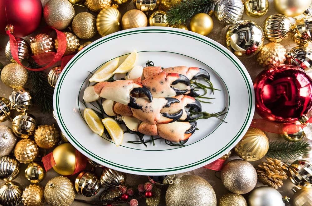 a plate of stone crab claws on a bed of red, gold and white christmas ornaments